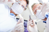 Zahnmedizinische Fachangestellte beugt sich über Patient in Magdeburg
